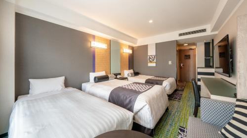 a hotel room with three beds and a television at New Otani Inn Sapporo in Sapporo
