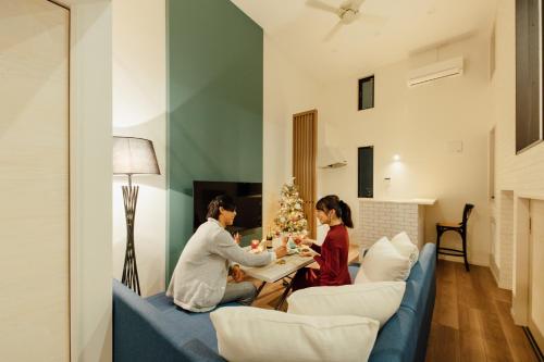 two women sitting in a living room with a christmas tree at YOUR ROOM 熊本駅 in Kumamoto