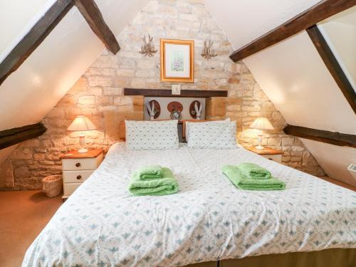 a bedroom with a bed with green towels on it at Hadcroft Cottage in Chipping Campden