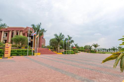 a brick road in front of a building with palm trees at Las Vegas Garden Hotel Mbarara in Mbarara
