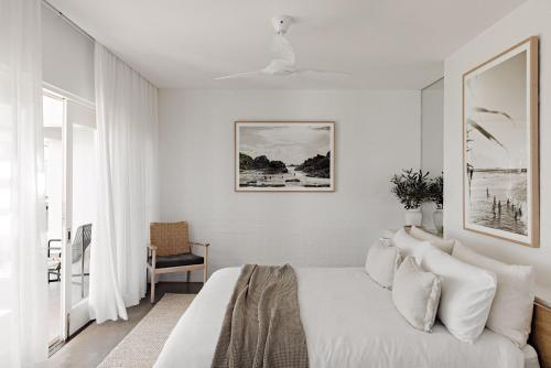 a white bedroom with a bed and a chair at Amileka in Federal