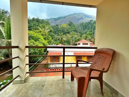 a chair on a balcony with a view of a mountain at Green Shades in Munnar