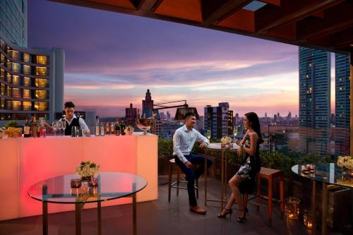 um grupo de pessoas sentadas num bar num telhado em Bangkok Marriott Marquis Queens Park em Bangkok