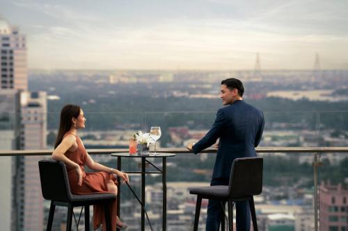 un hombre y una mujer sentados en una mesa en un edificio en Bangkok Marriott Marquis Queens Park, en Bangkok