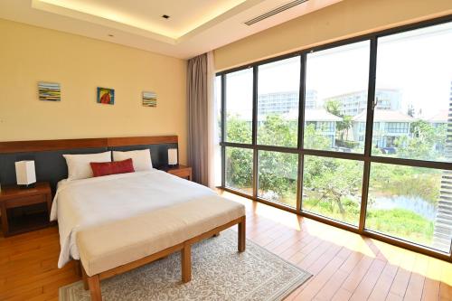 a bedroom with a bed and large windows at Pool Villas at Danang Beach with Private Pool in Danang