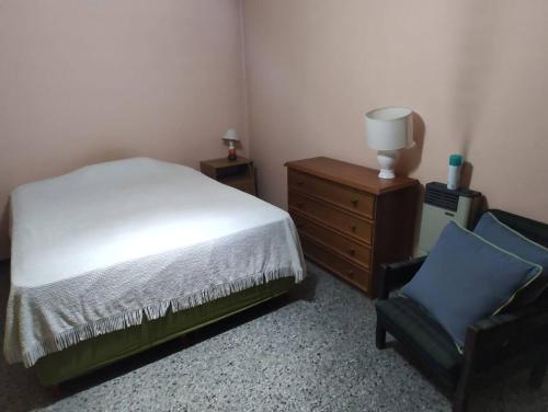 1 dormitorio con cama, silla y vestidor en Departamento Funcional en Guaymallén