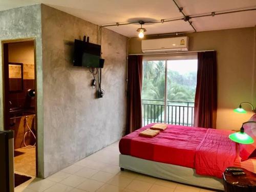 a bedroom with a red bed and a window at khaolak big bike&room for rent in Khao Lak