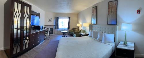 a bedroom with a white bed and a desk and a chair at Rocklin Park Hotel in Rocklin