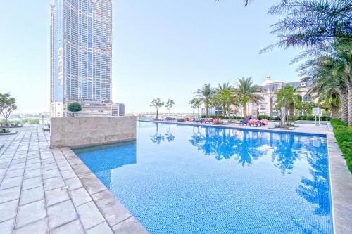 a swimming pool with palm trees and a tall building at bnbmehomes - Noora Tower in Dubai