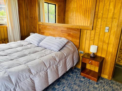 1 dormitorio con 1 cama y 1 mesa con lámpara en Cabańas Nordicas futrono, en Futrono