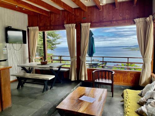 a living room with a table and a view of the ocean at Cabańas Nordicas futrono in Futrono