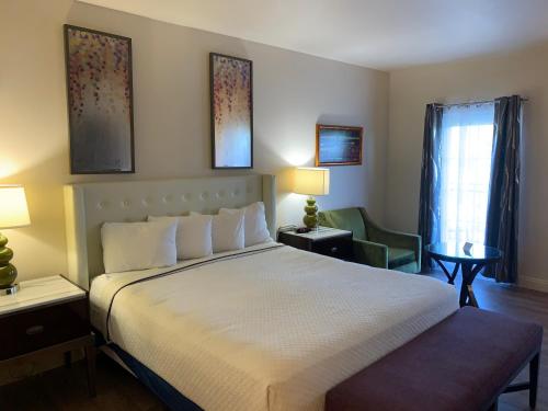 a bedroom with a large bed and a green chair at Rocklin Park Hotel, Trademark Collection by Wyndham in Rocklin