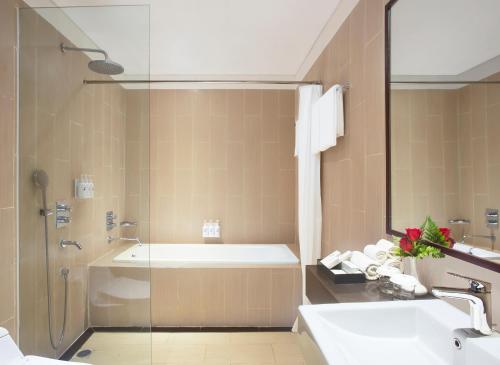 y baño con bañera, lavamanos y ducha. en Swiss-Belresidences Kalibata en Yakarta