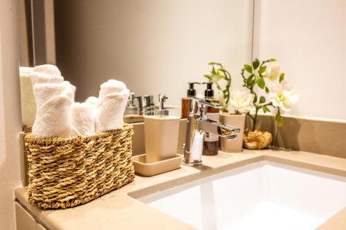 a bathroom sink with a basket of towels on it at Voyage Waters Edge Studio With Canal Views in Abu Dhabi