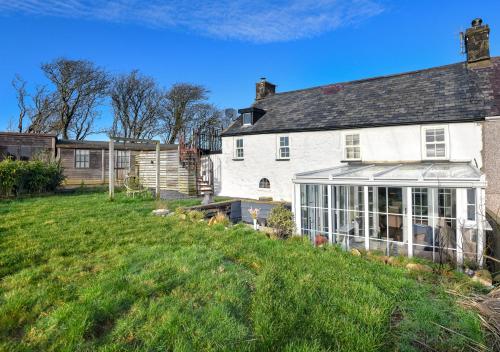 a white house with a greenhouse in a yard at Hideaway Tyn Llan in Bryncroes