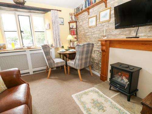 a living room with a fireplace and a table at Coln Cottage in Stow on the Wold