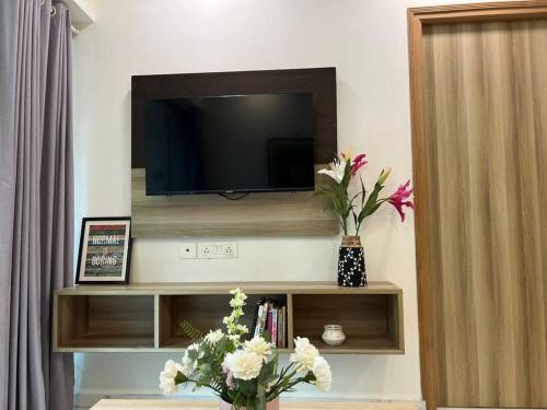 a living room with a television and flowers on a shelf at Jastcon, 19th Rd, Khar, Ambedkar Colony by Connekt Homes in Mumbai