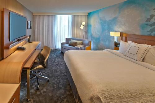 a hotel room with a bed and a desk with a television at Courtyard by Marriott Philadelphia City Avenue in Philadelphia