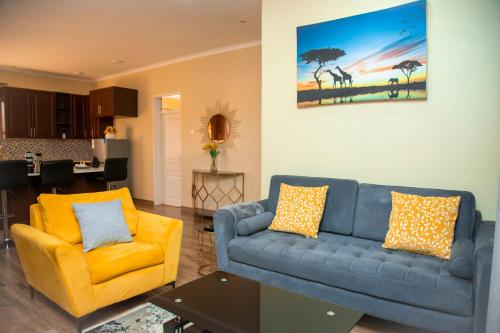 a living room with a blue couch and yellow chairs at Acacia Stay in Lilongwe