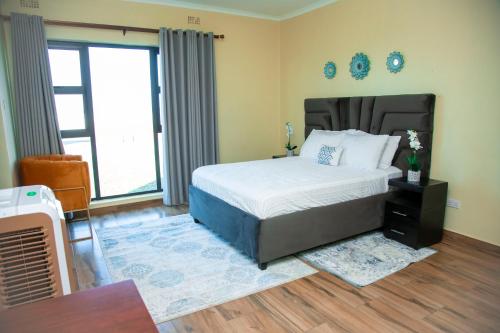 a bedroom with a bed and a large window at Acacia Stay in Lilongwe