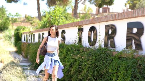 a woman walking down a path in front of a wall at Balneario de Alicún de las Torres in Villanueva de las Torres