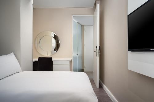 a bedroom with a white bed and a mirror at Protea Hotel by Marriott Cape Town Waterfront Breakwater Lodge in Cape Town