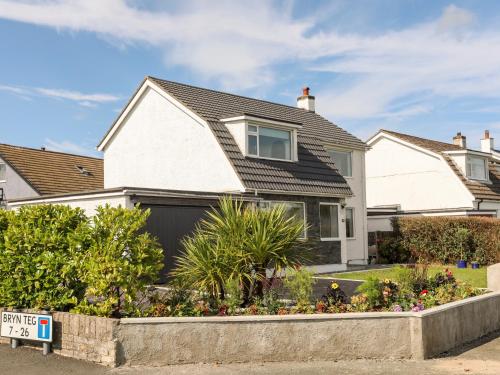 a white house with a black garage at Dolwyn in Menai Bridge
