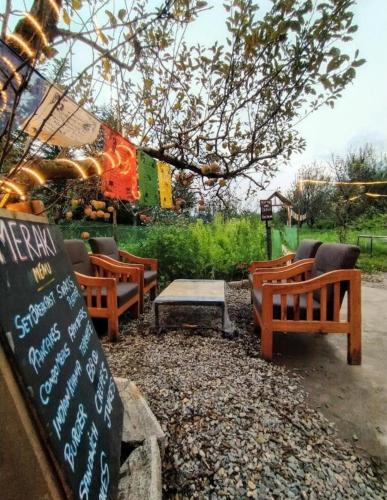a group of benches and a table and a sign at Farm Hostel & Camps in Manāli