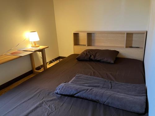 1 dormitorio con 1 cama y escritorio con lámpara en 九右衛門ゲストハウス(kuemon guesthouse), en Noroshi