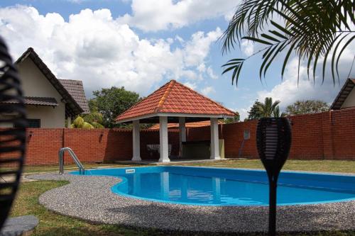 a swimming pool with a gazebo in a yard at Poolhomestay Raudhah Intan in Kampong Alor Gajah