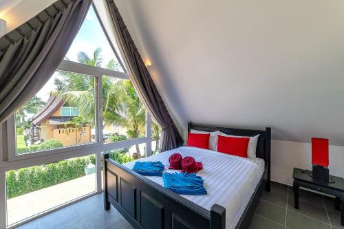 Un dormitorio con una cama con almohadas rojas y una gran ventana. en Villa of Siam en Ko Chang