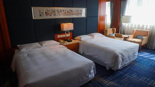 a hotel room with two beds and a chair at Four Points by Sheraton Suzhou in Suzhou