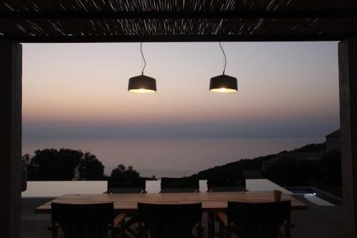 a dining room table with chairs and two lights at Aroa Eco Living Experience in Volimes