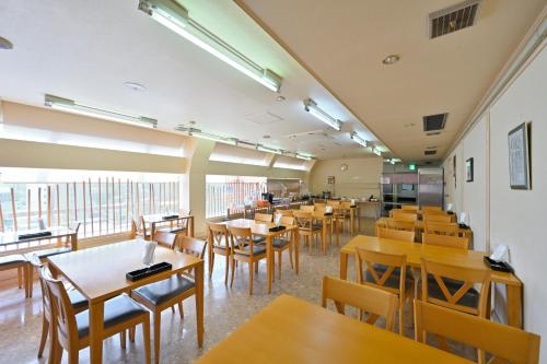 un ristorante con tavoli e sedie in legno in una stanza di Wakayama Daiichi Fuji Hotel a Wakayama
