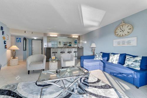 a living room with a blue couch and a clock at Beautiful Condo on the Beach in Freeport, Bahamas! in Pinders Point