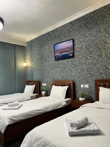 een kamer met drie bedden en een tv aan de muur bij Almaz Hotel Uzbekistan in Tasjkent
