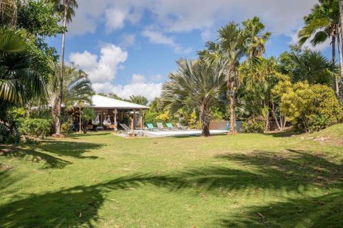 einem Park mit Palmen und einem Gebäude und einem Pool in der Unterkunft Villa Ma Vie La in Saint-François