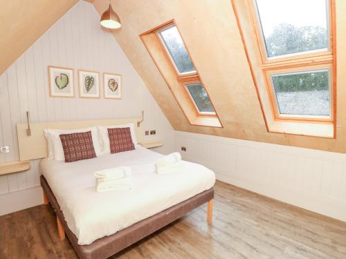 a bedroom with a bed in a attic with windows at Lodge 6 in Wareham