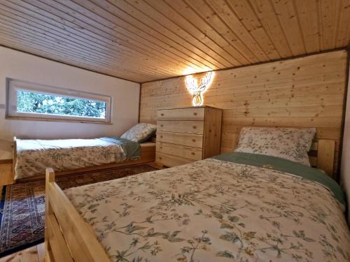 um quarto num chalé de madeira com uma cama e uma janela em Dębowe Siedlisko Chechłówka 