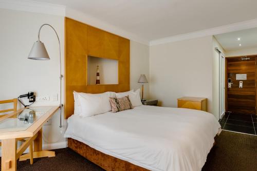 a bedroom with a large white bed and a desk at Protea Hotel by Marriott Knysna Quays in Knysna