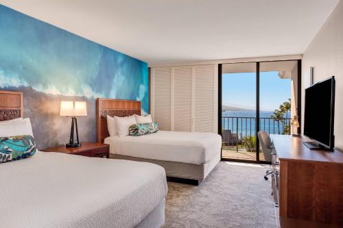 a hotel room with two beds and a balcony at Courtyard by Marriott King Kamehameha's Kona Beach Hotel in Kailua-Kona