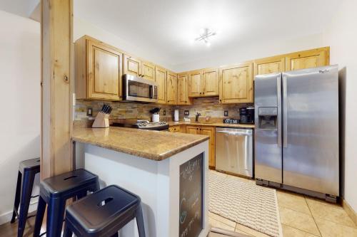 a kitchen with wooden cabinets and a stainless steel refrigerator at The Copperado at Copper Valley in Copper Mountain
