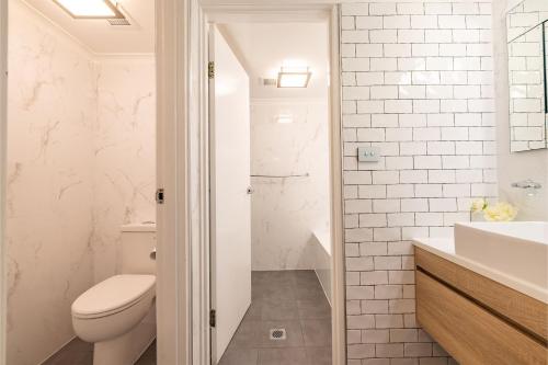 a white bathroom with a toilet and a sink at Bay Parklands 27 2 Gowrie Ave pool tennis court spa and views in Nelson Bay