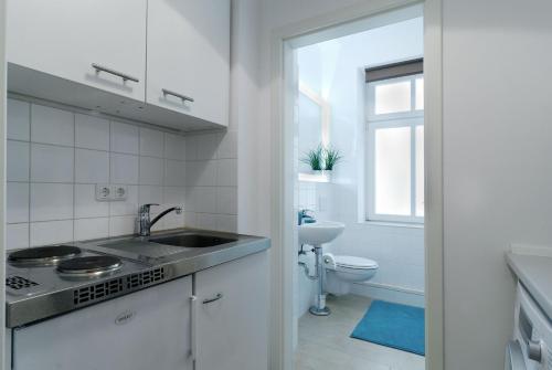 uma cozinha branca com um lavatório e um WC em Grand Central City Apartments Mitte Rosenthaler Platz em Berlim