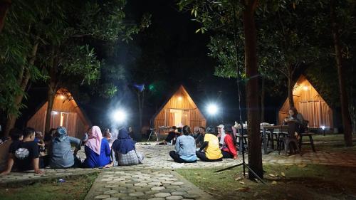 a group of people sitting on the ground in front of tents at "D'BAMBOO KAMP" Desa Wisata Ekang in Lagoi