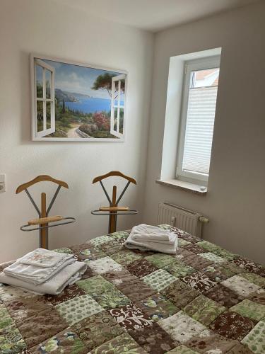 a bedroom with a bed with a quilt and two windows at Ferienwohnung Rhönperle Dermbach in Dermbach