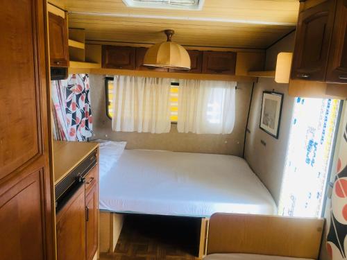 a small bedroom with a white bed in a trailer at Villaggio Mondial Camping in Metaponto