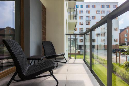 two chairs on a balcony with a view of a building at Bright & Stylish Apartment with Balcony 1,5 km to Gdańsk Main City by Renters in Gdańsk