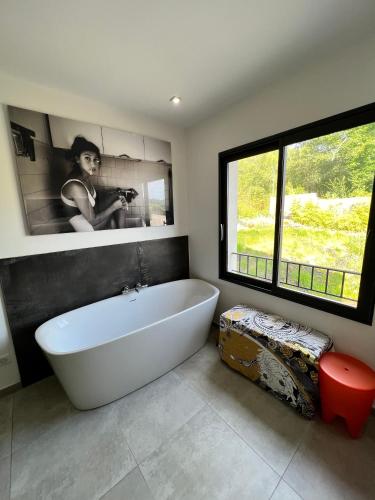 La salle de bains est pourvue d'une baignoire blanche et d'une grande fenêtre. dans l'établissement Luxury Villa with Pool en Provence, à Le Puy-Sainte-Réparade