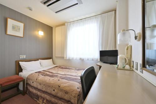 a hotel room with a bed and a desk and a window at Wakayama Daiichi Fuji Hotel in Wakayama